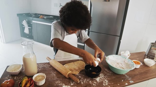 Young family cooking food in kitchen. Happy Little girl with her mother mixing batter. Mother and Little boy preparing the dough. Happy family in the kitchen and junior chef Concept. Cinematic 4k.