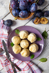 Dumplings stuffed with plums served with cream and brown sugar