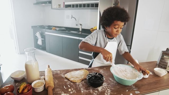 Young family cooking food in kitchen. Happy Little girl with her mother mixing batter. Mother and Little boy preparing the dough. Happy family in the kitchen and junior chef Concept. Cinematic 4k.