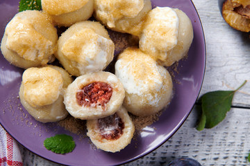 Dumplings stuffed with plums served with cream and brown sugar