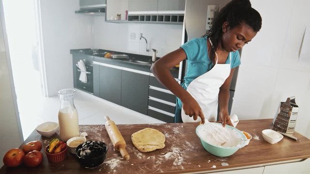 Young family cooking food in kitchen. Happy Little girl with her mother mixing batter. Mother and Little boy preparing the dough. Happy family in the kitchen and junior chef Concept. Cinematic 4k.