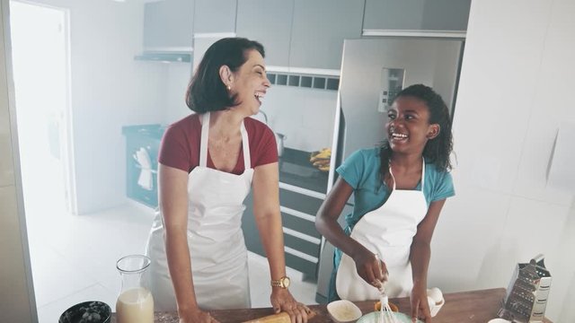 Young family cooking food in kitchen. Happy Little girl with her mother mixing batter. Mother and Little boy preparing the dough. Happy family in the kitchen and junior chef Concept. Cinematic 4k.