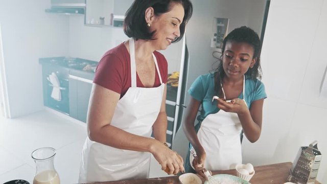 Young family cooking food in kitchen. Happy Little girl with her mother mixing batter. Mother and Little boy preparing the dough. Happy family in the kitchen and junior chef Concept. Cinematic 4k.