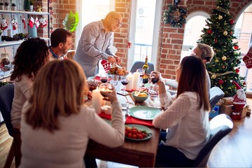 Family and friends dining at home celebrating christmas eve with traditional food and decoration, preparing turkey for dinner