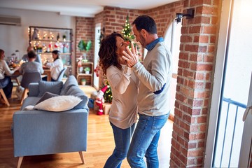 Family and friends dining at home celebrating christmas eve with traditional food and decoration, romantic couple dancing in love