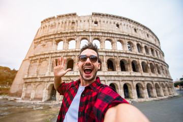 Happy tourist taking a selfie in front of the Colosseum in Rome, Italy