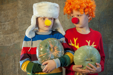 Two boys brothers in bright festive attire are holding pumpkins in their hands. Children dictate their message to Santa Claus before Christmas. Pupils sing songs and talk about successful studies
