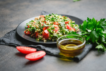 Traditional oriental salad Tabbouleh with bulgur and parsley on a dark background