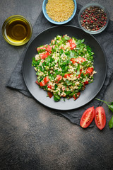Traditional oriental salad Tabbouleh with bulgur and parsley on a dark background top view.