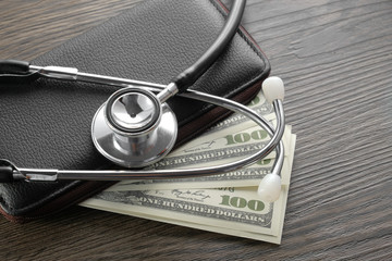 Fototapeta Stethoscope on wallet and dollar banknote money. Concept of health care costs finance obraz