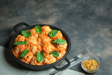 Meatballs in a pan with spinach leaves on a dark background copy space.