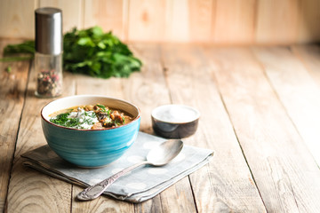 Homemade soup with porcini mushrooms croutons and herbs on a light wooden background