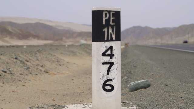 Panamericana highway in a desert in Peru with a pylon with the highway number PE1N. South America. PERU