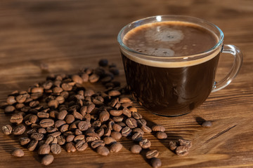 Coffee cup and coffee beans on wooden table. Selective focus
