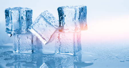 Naklejka na ściany i meble Ice cubes square with drops water clean on blue background with sun light