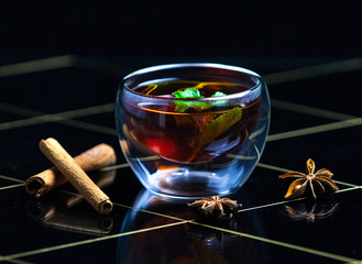 tea with cinnamon in a transparent glass and candles