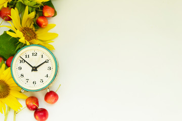 Autumn background. Border of yellow sunflower flowers, red apples and alarm clock. School concept, proper nutrition. There is a place for text.