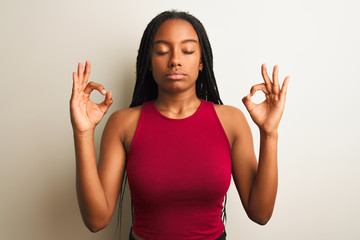 African american woman wearing red casual t-shirt standing over isolated white background relax and smiling with eyes closed doing meditation gesture with fingers. Yoga concept.