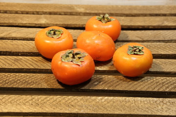 Ripe orange persimmons on brown wooden background