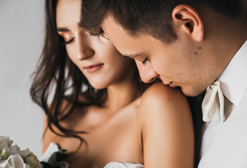 Loving man tenderly kisses his bride on the shoulder