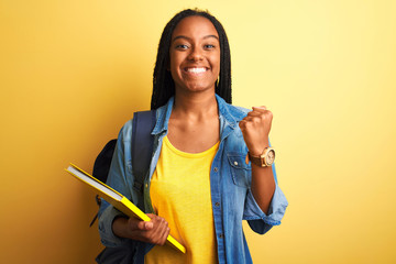 African american student woman wearing backpack and book over isolated yellow background screaming...