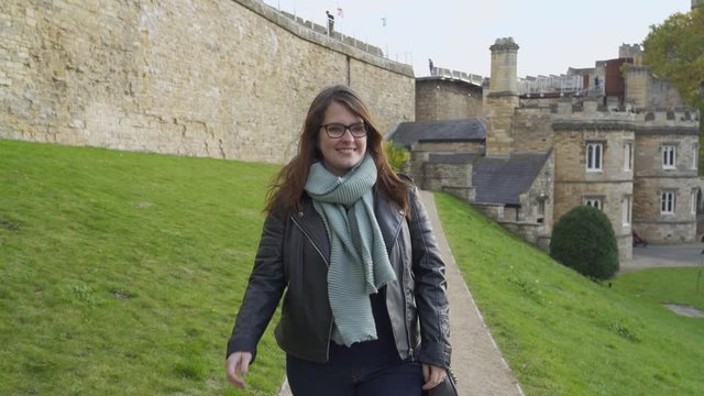 Woman walking towards to the camera, inside of  the Lincoln touristic Castle, England.