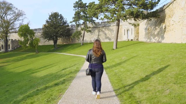 Woman Walking by the walk path, inside the touristic Lincoln Castle, England, Wide angle