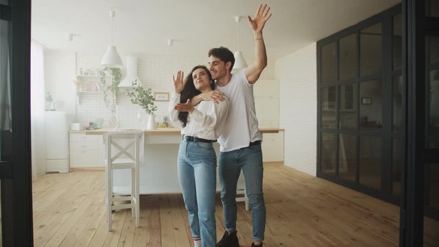 Happy homeowners planning house interior. Young married couple hugging at home.