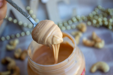 Creamy peanut butter and spoon on background