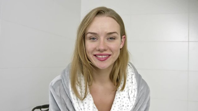 Casual woman in bathrobe smiling to camera.