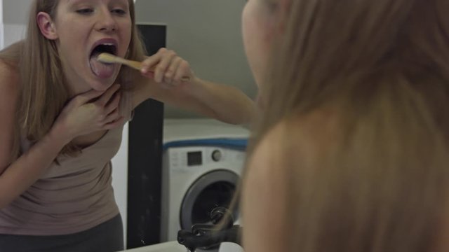 A woman washes her tongue with a bamboo toothbrush