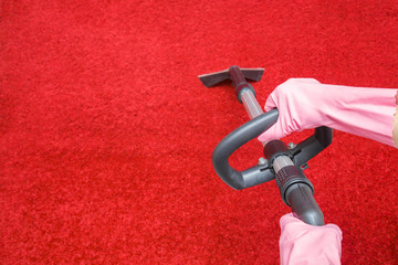 Cleaner hands in rubber protective gloves cleaning red shaggy carpet with professionally extraction...