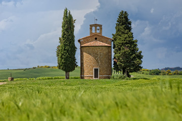 Fototapeta na wymiar In the colorful southern Tuscany near the village of Vitaleta, there is the charming, small chapel of the Madonna di Vitaleta, San Quirico d'Orcia, Siena, Tuscany, Italy