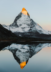 Alpenglow on iconic mountain peak Matterhorn in Swiss Alps, reflected in tranquil lake Riffelsee on high altitude. Unique travel destination in Alps. The beauty of nature simplicity concept. 