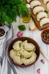 Boiled Vegan dumplings (vareniki) with potatoes and fried mushrooms with onions in a bowl on a white wooden background.   Traditional Russian and Ukrainian dish. Lenten dish.