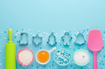 ingredients for baking and kitchen tools with cookie cutter on blue background, flat lay