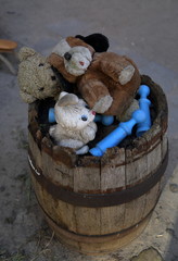 Stare, wyrzucone zabawki pluszowe i inne leżą ściśnięte w starej drewnianej beczce, widok z...