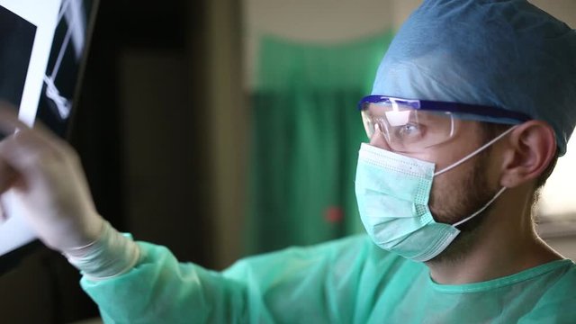 surgeon examines fluorography images on a monitor in an operating room of a medical office.