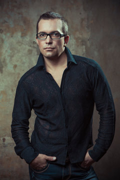 confident man in the black shirt and glasses on the background of vintage wall