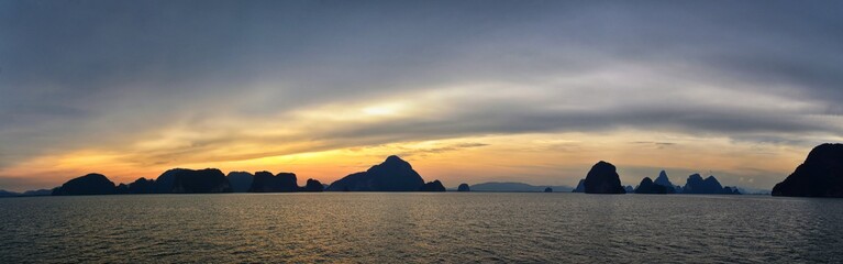Naklejka na ściany i meble Islands Sunset, Ocean panorama views near Phuket with deep Red, Orange, Purple and Blue, mountains, twilight in Thailand. Including Phi Phi, Ko Rang Yai, Ko Li Pe and other islands. Asia.