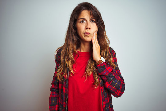 Young beautiful woman wearing red t-shirt and jacket standing over white isolated background touching mouth with hand with painful expression because of toothache or dental illness on teeth