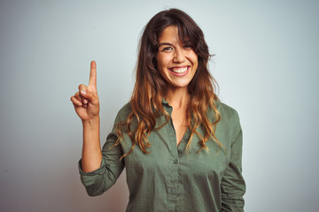 Young beautiful woman wearing green shirt standing over grey isolated background showing and...