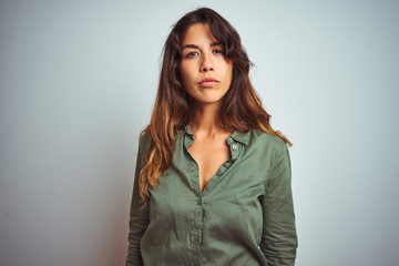 Fototapeta premium Young beautiful woman wearing green shirt standing over grey isolated background Relaxed with serious expression on face. Simple and natural looking at the camera.