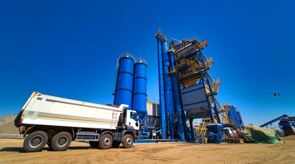 The truck is ready to load gravel or sand in concrete station. Asphalt production, Road construction. Blue sky background.