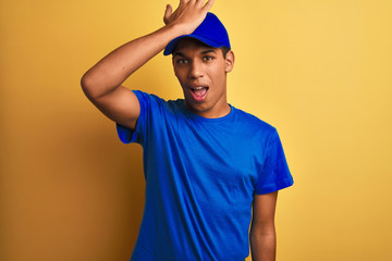 Fototapeta premium Young handsome arab delivery man standing over isolated yellow background surprised with hand on head for mistake, remember error. Forgot, bad memory concept.