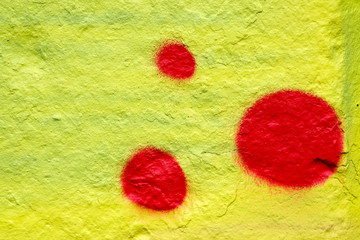 Spot of red paint on a yellow background. Abstract background of painted stone wall. red circles on a yellow background.