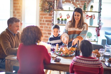 Beautiful family smiling happy and confident. One of them curving roasted turkey celebrating christmas at home