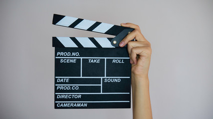 Female hands holding movie clapper isolated on gray background.