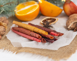 Different fruit leather on parchment paper, burlap and a white board.