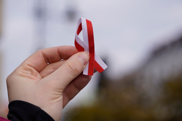 hand with red and white ribbon on background. Flag background national holiday country november...